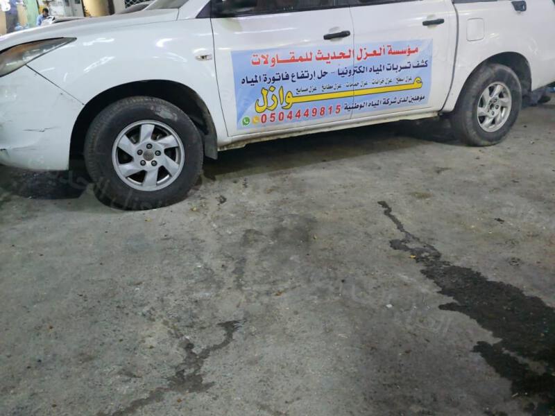 سيارة مؤسسة العزل الحديث عليها اسم المؤسسة وخدماتها واقفة أمام المحل